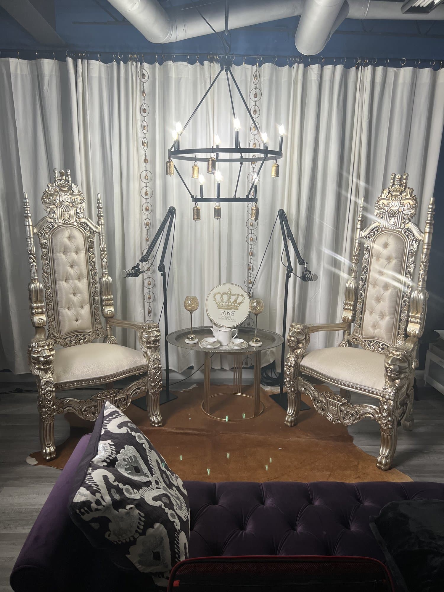 Empty podcast set with a tall tufted throne chair facing a guest seat.